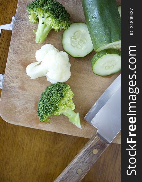 Fresh vegetables with knife on cutting board