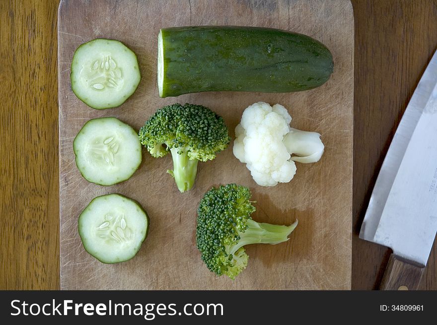 Fresh green vegetables with knife on wooden board background. Fresh green vegetables with knife on wooden board background