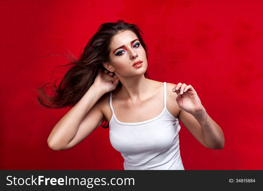 Girl with flying hair and colorful eyeshadow on red background. Girl with flying hair and colorful eyeshadow on red background