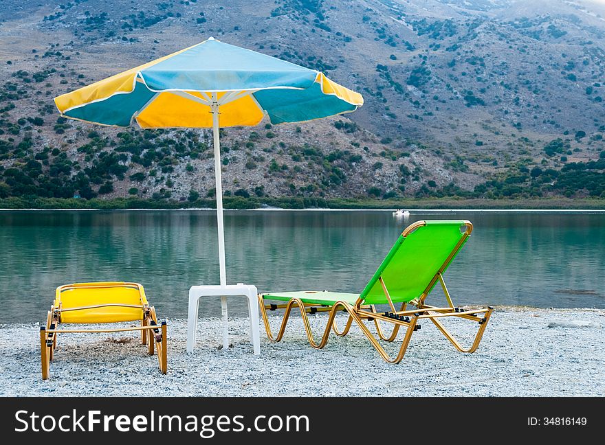 Two beach chairs and a beach umbrella on the shore of Lake. Two beach chairs and a beach umbrella on the shore of Lake