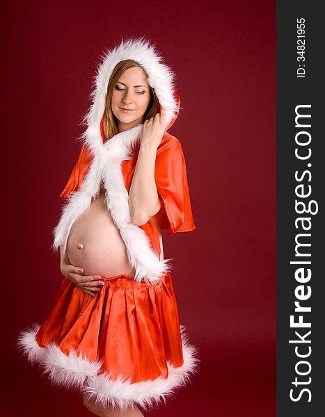 Beautiful pregnant woman in suit Snow Maiden on red background