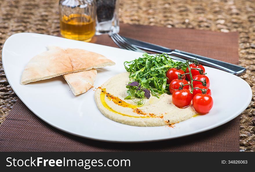 Plate with hummus dip and pita bread, a common tapas or starter dish in middle eastern cuisine. Plate with hummus dip and pita bread, a common tapas or starter dish in middle eastern cuisine