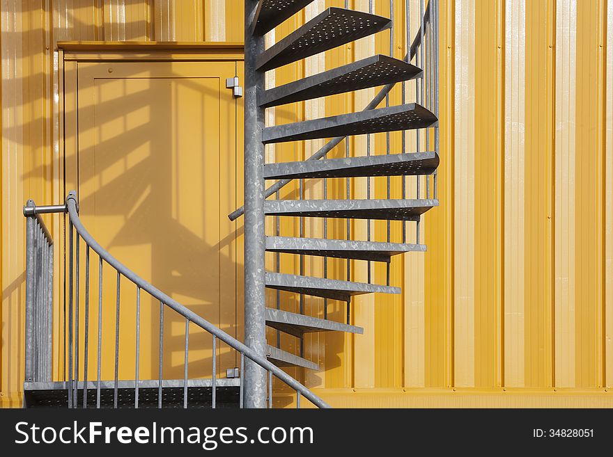 Yellow building with a spiral metal staircase. Emergency exit. Yellow building with a spiral metal staircase. Emergency exit