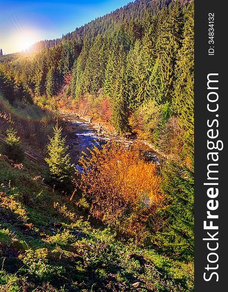 River Flows By Rocky Shore Near The Autumn Mountain Forest