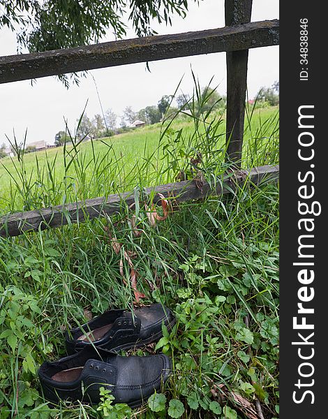 Abandoned black boots near the rural fence. Abandoned black boots near the rural fence