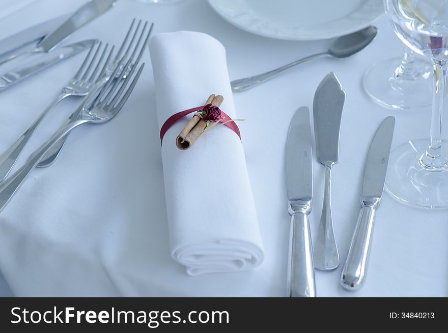 A towel with ribbon ant cynammon, forks and knives on a wedding table. A towel with ribbon ant cynammon, forks and knives on a wedding table
