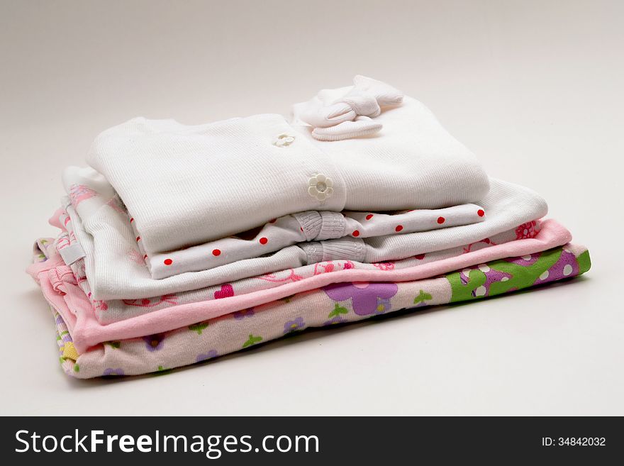 Baby clothes on a pink blanket on gray background. Baby clothes on a pink blanket on gray background