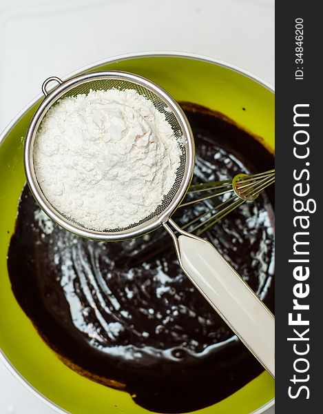 Sieving flour in dark chocolate batter. Sieving flour in dark chocolate batter