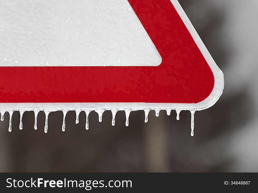 A road sign with icicles on a background of a dark forest