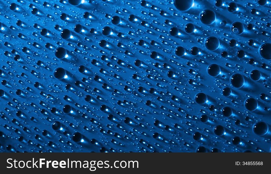 Blue background. Side lighting. Many water drops, highlights and shadows. Three large drops crawling down one after another. Blue background. Side lighting. Many water drops, highlights and shadows. Three large drops crawling down one after another