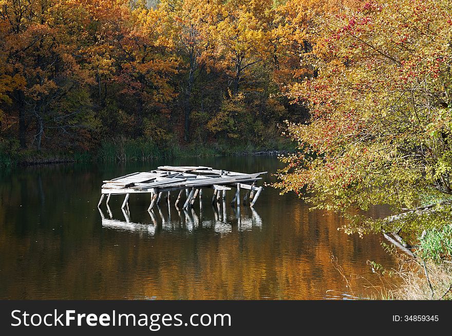 Forest pond. The broken pier. Autumn forest