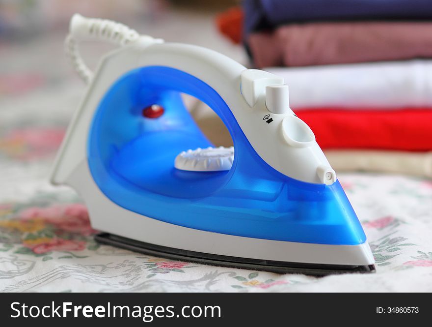 Blue steam iron and stack of cloth