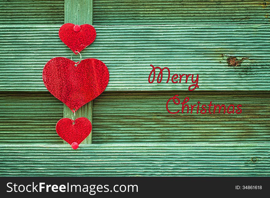 Red hearts on green wooden background with Merry christmas letters. Red hearts on green wooden background with Merry christmas letters