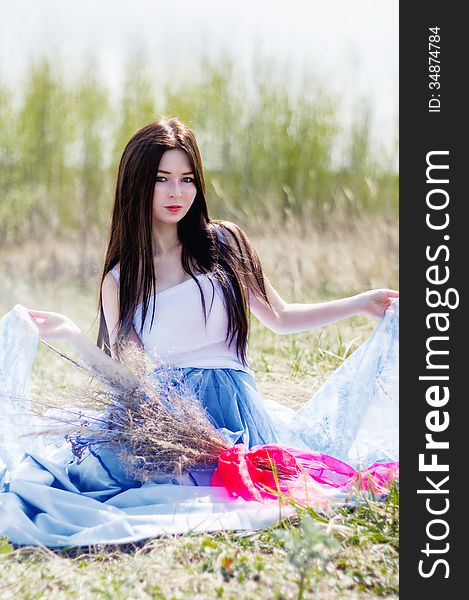 Young beautiful girl sitting in spring field. Young beautiful girl sitting in spring field
