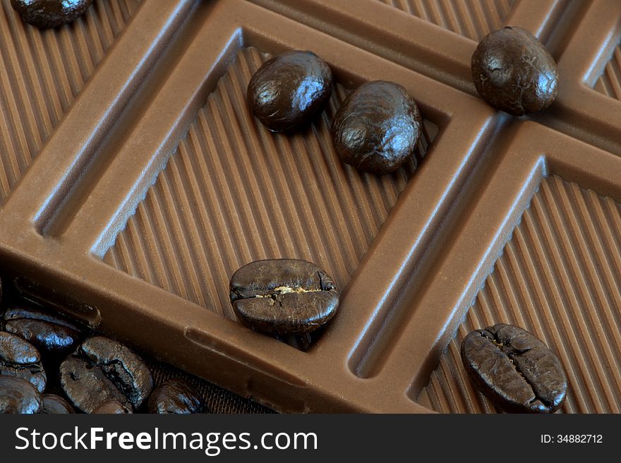 Coffee grains are on the bar of chocolate. Coffee grains are on the bar of chocolate