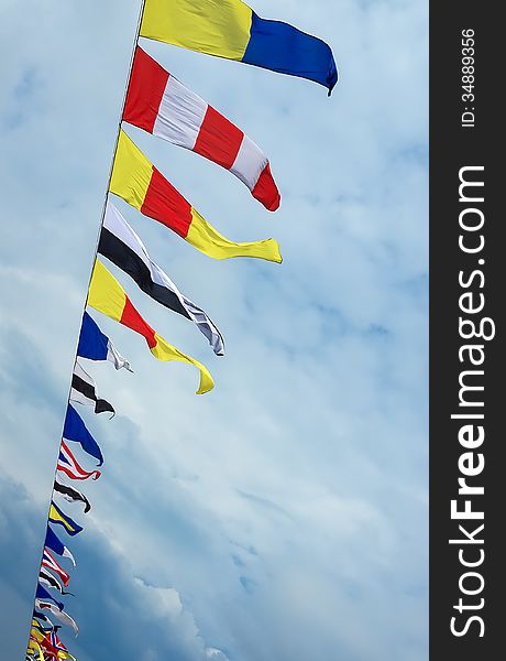 Colorful signal flags in the wind at sky background. Marine colored nautical flags against the sky.