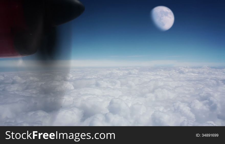 View from turboprop aircraft, which flies above the clouds. Bright sunny blue sky. Large moon. View from turboprop aircraft, which flies above the clouds. Bright sunny blue sky. Large moon