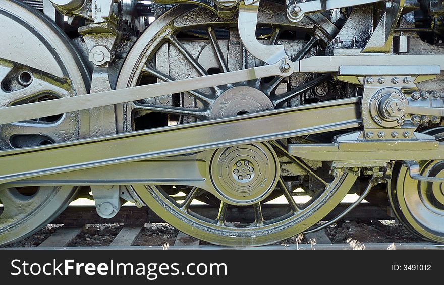 Photo of wheels and gears on an old-fashioned train engine. Photo of wheels and gears on an old-fashioned train engine
