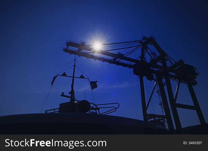 Shapes of cranes at a cargo harbor in backlight. Shapes of cranes at a cargo harbor in backlight