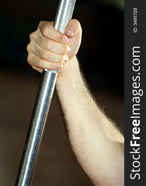 One hand held close a Yoke in Vertical Position / Exercises in the gym / Blur Dark Background. One hand held close a Yoke in Vertical Position / Exercises in the gym / Blur Dark Background