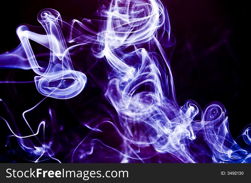 Swirling, twirling plumes of lilac or lavender colored smoke on a black background. Swirling, twirling plumes of lilac or lavender colored smoke on a black background.
