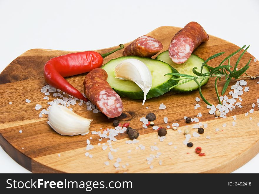 Various spices and sausages on a wooden plate. Various spices and sausages on a wooden plate