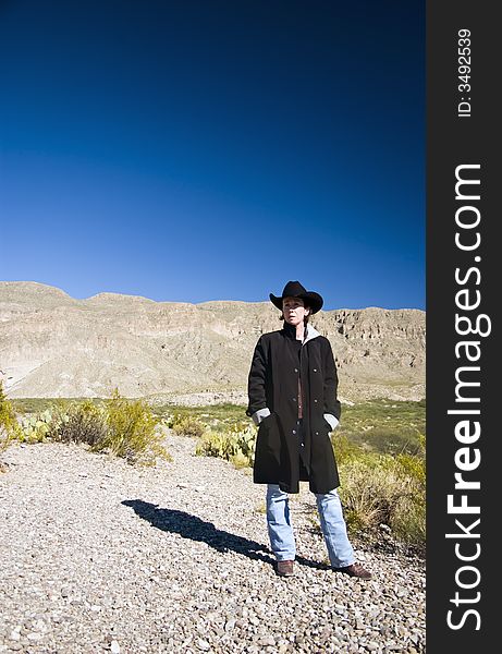 A woman dressed in a black coat and black western hat observing her surroundings. A woman dressed in a black coat and black western hat observing her surroundings.