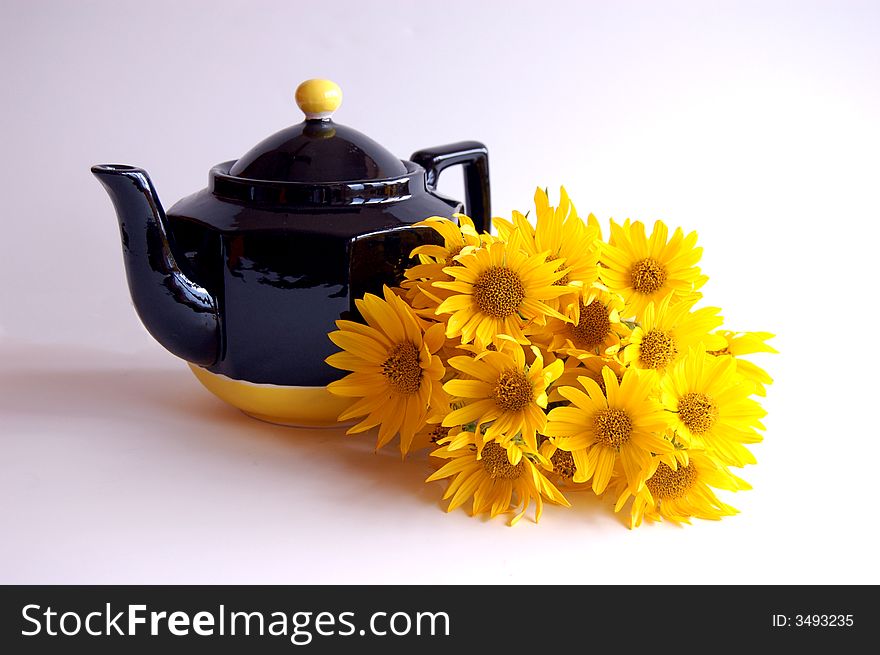 Bright, cheery still life of a black and white teapot and a bunch of sunflowers on a white backgound. Bright, cheery still life of a black and white teapot and a bunch of sunflowers on a white backgound.