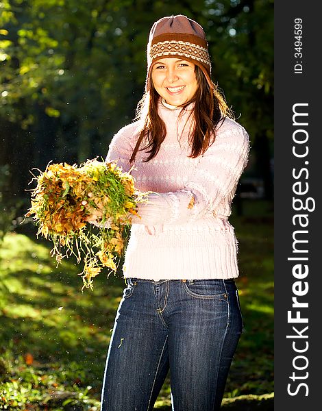 Beautiful young girl holding leaves and grass in her hands. Beautiful young girl holding leaves and grass in her hands