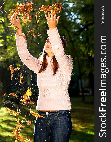 Beautiful young girl throwing golden leaves in the air - great smile. Beautiful young girl throwing golden leaves in the air - great smile