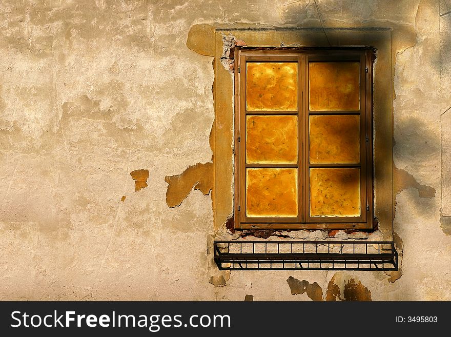 Old window with ruined yellow wall