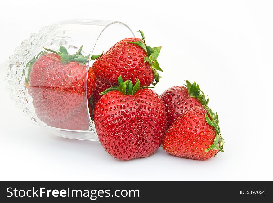 Glass of ripe strawberries spilling out isolated on white. Glass of ripe strawberries spilling out isolated on white