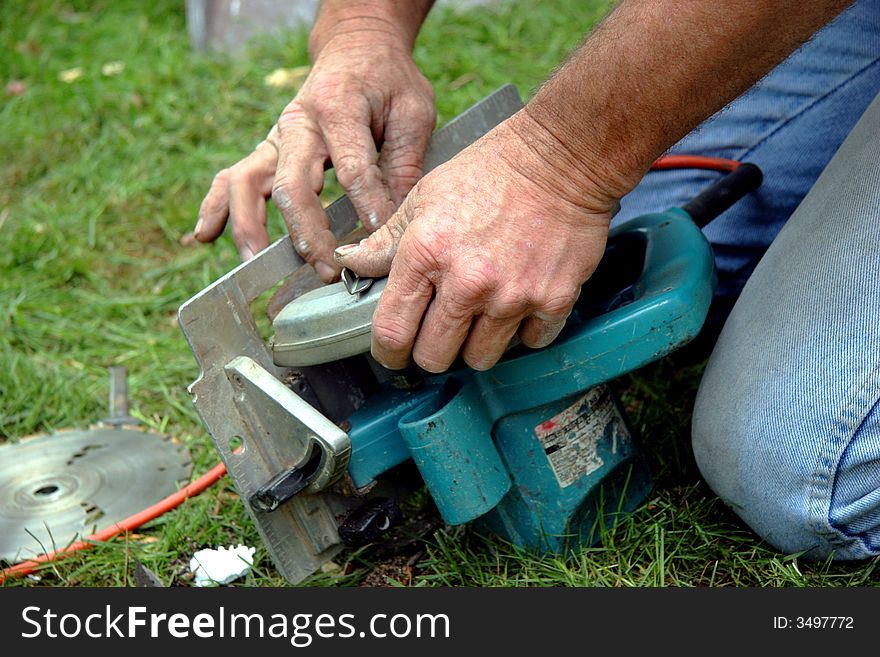 The hands of a worker as he changes a circular saw blade. The hands of a worker as he changes a circular saw blade