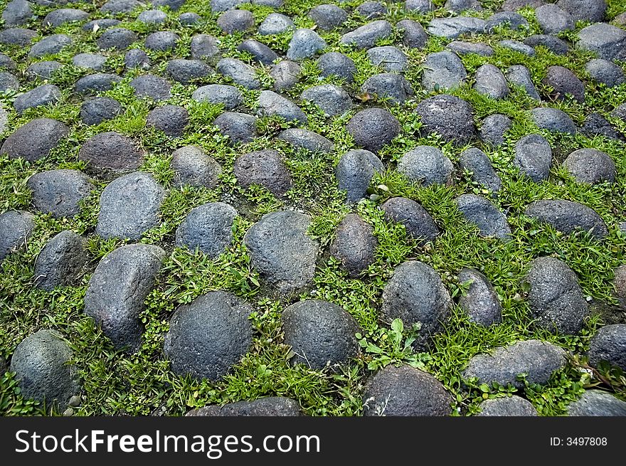 A close up of a typical medieval paving in Bologna - Italy - with grass and pebbles. Cobbled paving. A close up of a typical medieval paving in Bologna - Italy - with grass and pebbles. Cobbled paving.