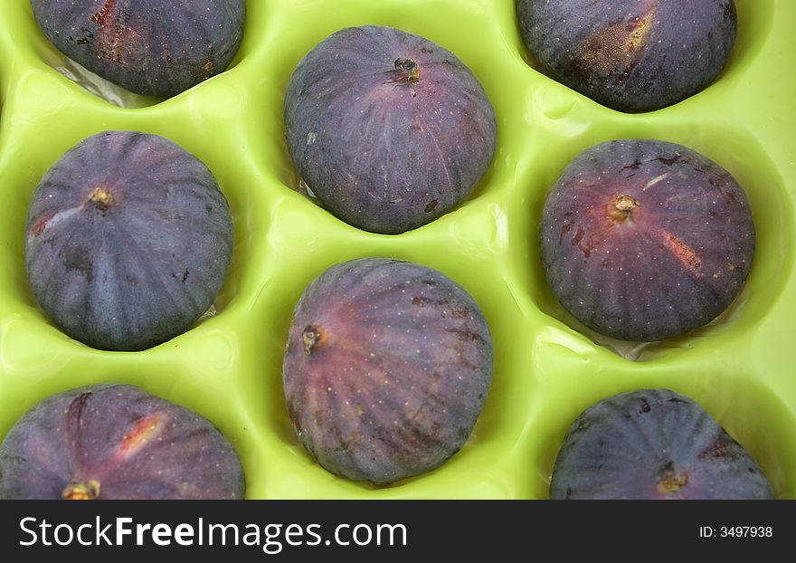 Ripe fresh figs in green packaging background