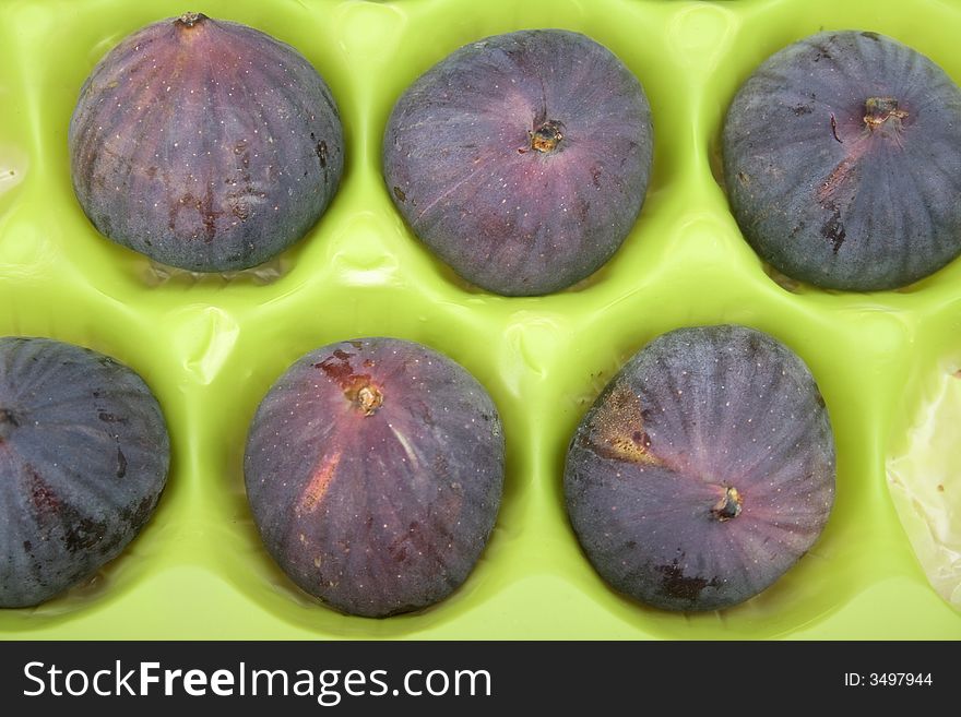 Ripe fresh figs in green packaging background