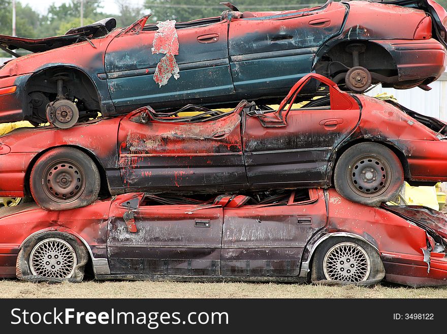 Cars used in a monster truck show are neatly stacked. Cars used in a monster truck show are neatly stacked