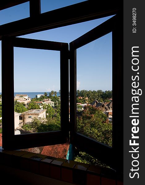 A window opens out onto a view of a tropical fishing village. A window opens out onto a view of a tropical fishing village.