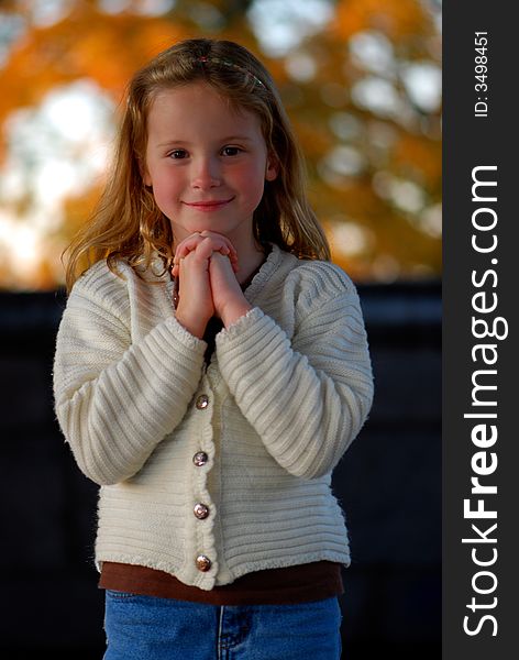 A pretty little girl with a sweet smile poses for an outdoor portrait. A pretty little girl with a sweet smile poses for an outdoor portrait.