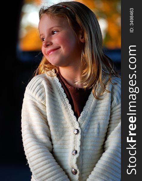 A pretty little girl with a sweet smile poses for an outdoor portrait. A pretty little girl with a sweet smile poses for an outdoor portrait.