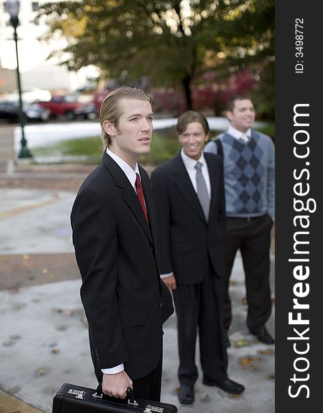 Three well dressed businessmen standing in a row smiling. Three well dressed businessmen standing in a row smiling