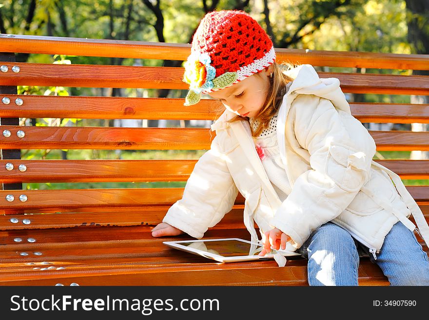 Happy child holding tablet PC in autumn park. Happy child holding tablet PC in autumn park