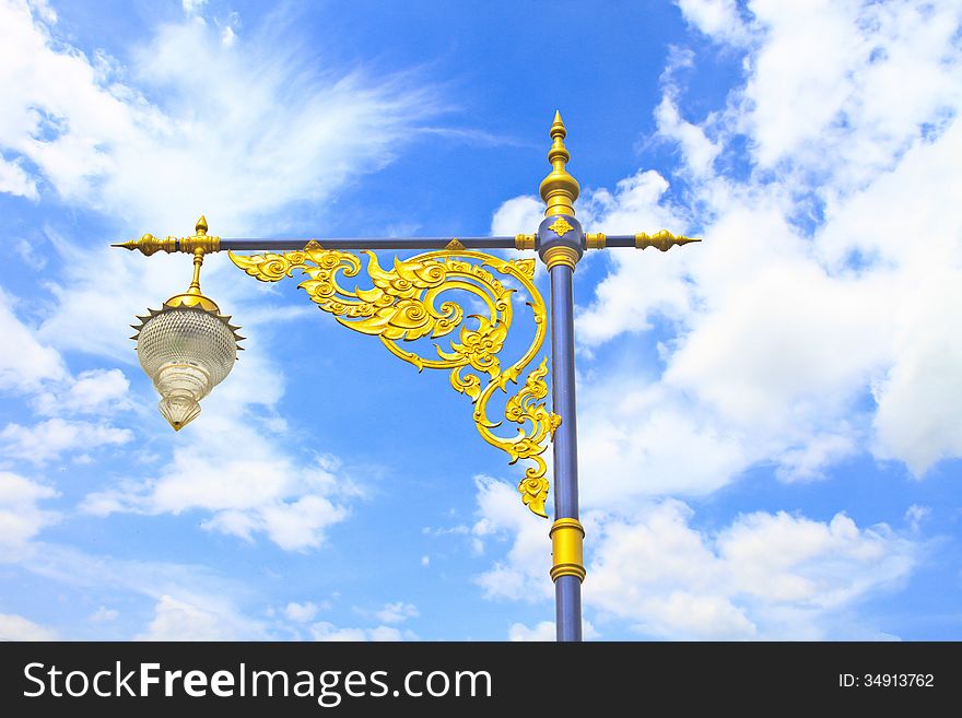 Golden lighting pole on blue sky, Thai style statue