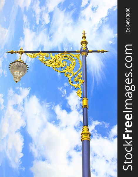 Golden lighting pole on blue sky, Thai style statue