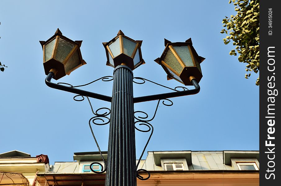 A street lamp is photographed from below against the blue sky. A street lamp is photographed from below against the blue sky.