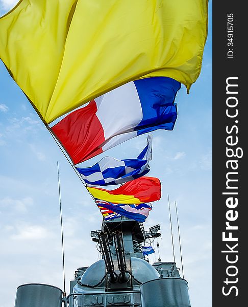 Colorful nautical signal flags in the wind at sky background. Marine colored flags against the sky on the mast of the military ship.