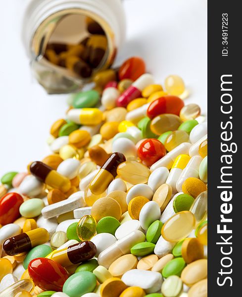 Many colorful medicines spilling out of a bottle