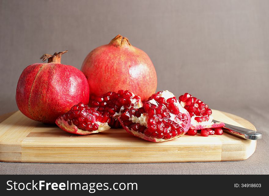 Pomegranate, divided into pieces on a cutting board. Pomegranate, divided into pieces on a cutting board