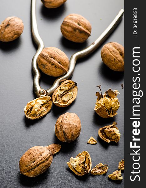 Walnuts and nutcracker on black glossy background