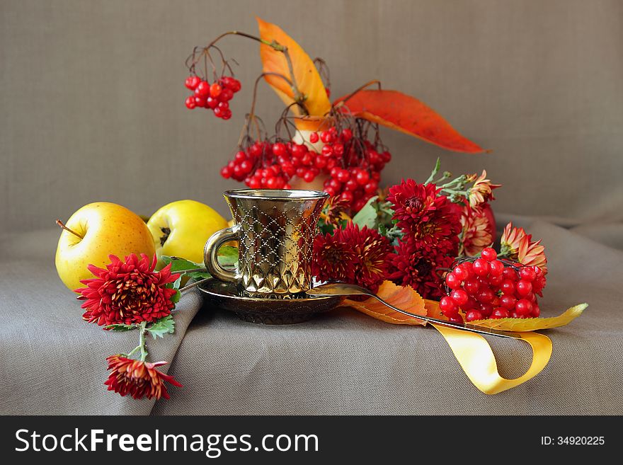 A cup of coffee in beautiful cup on the background of autumn flowers and berries. A cup of coffee in beautiful cup on the background of autumn flowers and berries